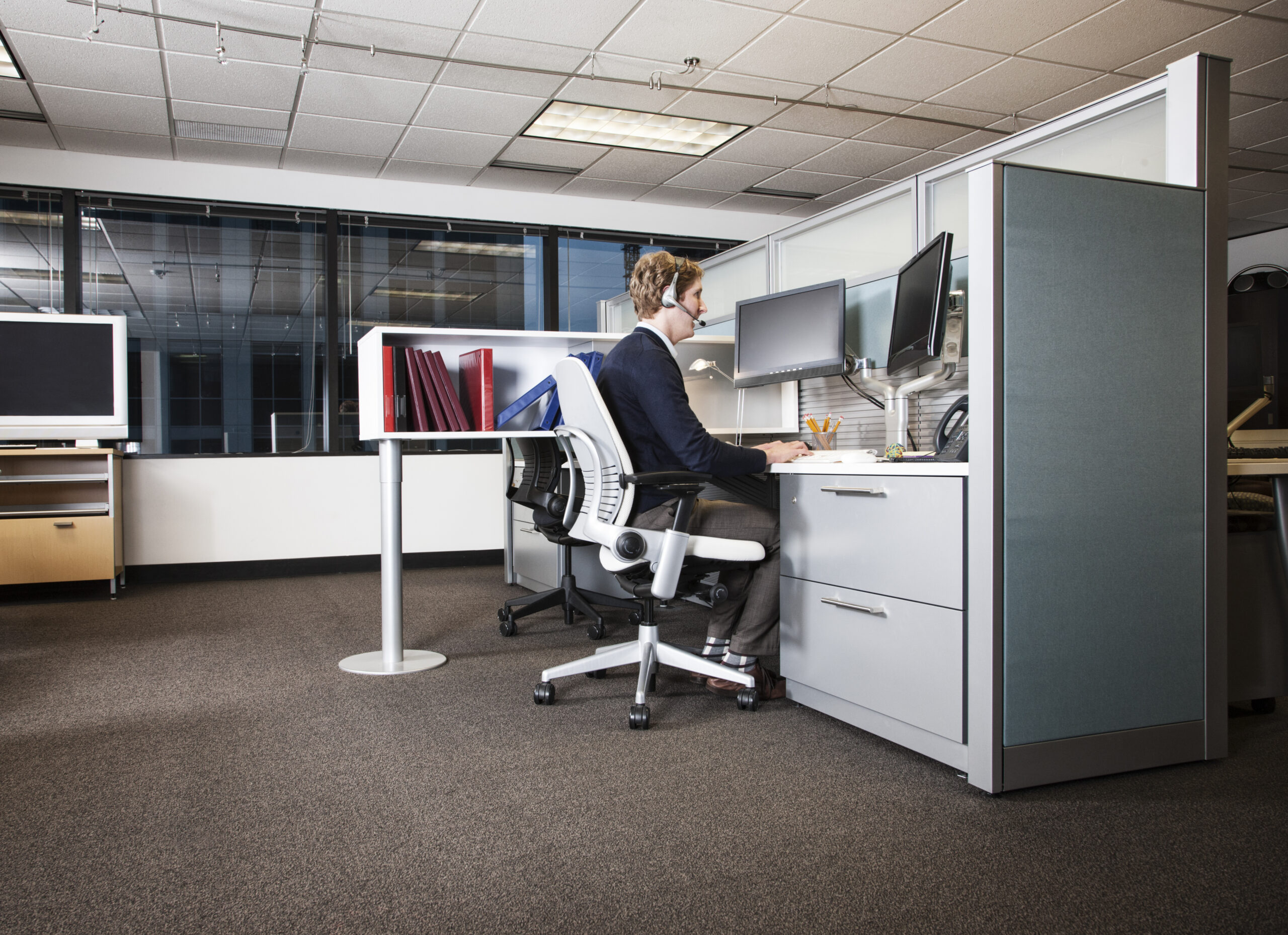 Caucasian businessman working at his computer while sitting in his cubicle office.